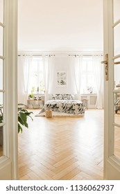 Loft Bedroom Interior With A Herringbone Parquet, Bed, Windows And Plant. View Through The Door