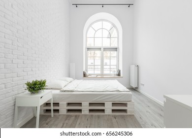 Loft Bedroom With White Brick Wall, Pallet Bed And Half Circle Window