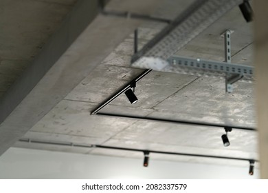 Loft interior style fragment. Black track lights on a concrete ceiling. Led track spotlights and corrugated wiring on the ceiling.