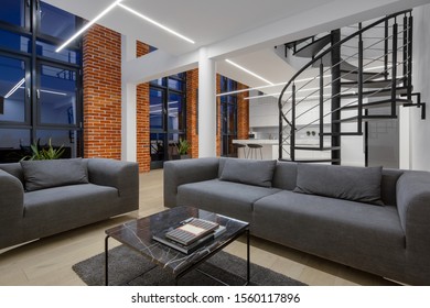 Loft style apartment with living room open to kitchen, spiral stairs, brick walls and big windows - Powered by Shutterstock