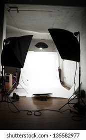 Loft Turned Into A Photographer Studio Ready For Action. White Paper Limbo Surrounded By Lighting Equipment.