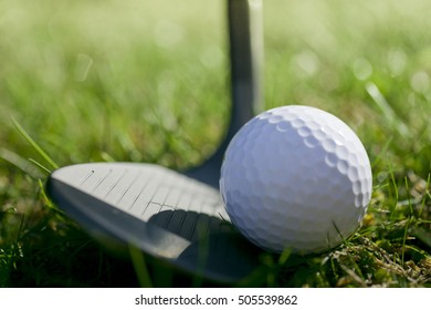 Lofted Wedge Resting Behind A Golf Ball