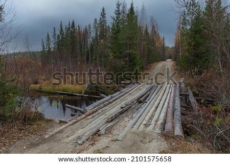 Log bridge across the black river in the Karelian wilderness