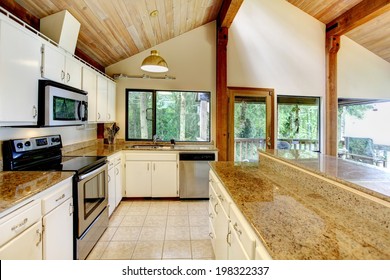 Log Cabin House Interior. View Of White Kitchen Room With Steel Appliances