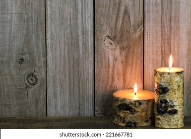 Log candles burning by rustic wooden background