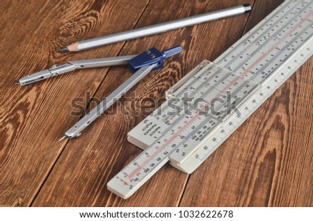 Logarithmic ruler, compasses, pencil on a wooden table. Stationery for engineers and students.
