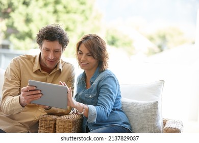 Logging Into Their Joint Email Account. Shot Of A Husband And Wife Using A Digital Tablet Together At Home.