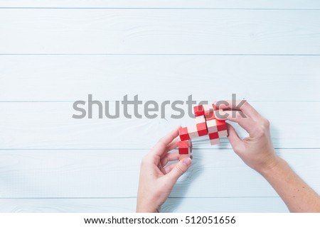 Logic background. The concept of logical thinking. Wooden colorful cube, puzzle. Hands holding wooden conundrum.