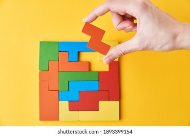 Logical thinking and finishing task concept. Woman hand adding last missing wooden block to finish a puzzle