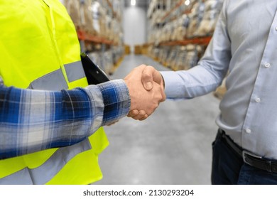 logistic business and cooperation concept - close up of manual worker and businessman shaking hands and making deal at warehouse - Powered by Shutterstock