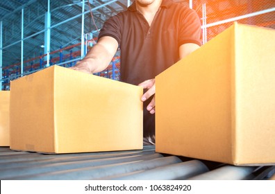 Logistic and warehouse, warehouse worker sorting a package cardboard boxes on conveyor rollors in distribution center.