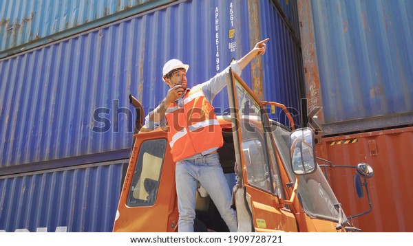 Logistic worker engineer man in truck car\
cabin working and talking to colleagues by walky talky in cargo\
container warehouse industry site in transportation concept.\
Business people\
lifestyle.