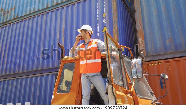 Logistic worker engineer man in truck car\
cabin working and talking to colleagues by walky talky in cargo\
container warehouse industry site in transportation concept.\
Business people\
lifestyle.
