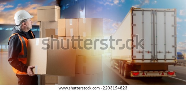 Logistics business. Man works in logistics industry.\
Man with boxes and truck. Logistics company employee. Loader is\
holding box. Blurred truck is driving on road. Warehouse worker\
preparing to load