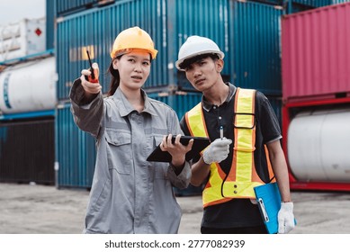 Logistics engineer directing worker at cargo container shipping yard. Teamwork communication using walkie-talkie and tablet for supply chain transport management.