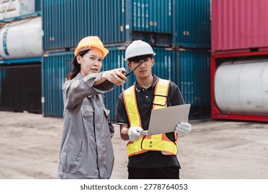 Logistics engineer directing worker at cargo container shipping yard. Teamwork communication using walkie-talkie and tablet for supply chain transport management.