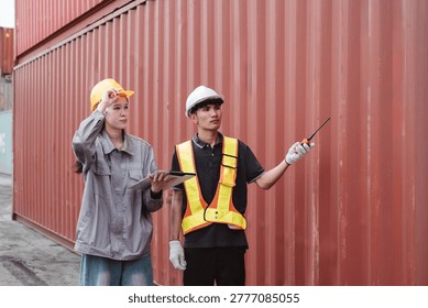 Logistics engineer pointing and directing worker at container yard. Female supervisor and male operator checking cargo supply chain transport data.