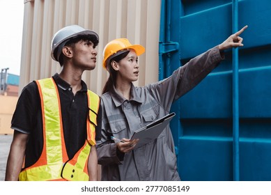 Logistics engineer pointing and directing worker at container yard. Female supervisor with clipboard checking cargo supply chain transport data.