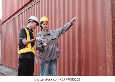 Logistics engineer pointing and directing worker at container yard. Female supervisor and male operator checking cargo supply chain transport data.
