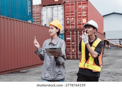Logistics engineers communicating and directing cargo transport. Female supervisor with clipboard and male worker using walkie-talkie at container yard.