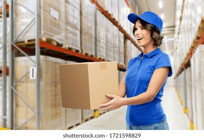 Logistics, Mail Service And Shipment Concept - Happy Smiling Delivery Girl With Parcel Box In Blue Uniform Over Warehouse Background