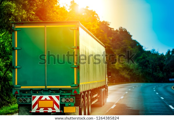 Logistics transport industry concept, motion\
truck running in road on hills, cargo business truck driving fast\
on highway on blurred tree and sharp\
curve.