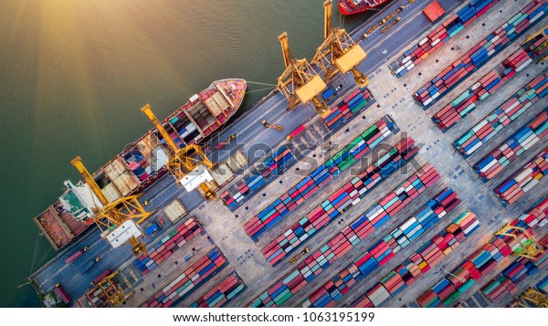 Logistics and\
transportation of Container Cargo ship and Cargo plane with working\
crane bridge in shipyard at sunrise, logistic import export and\
transport industry\
background