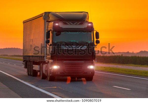 logistics truck\
on the highway at dawn, orange\
sky