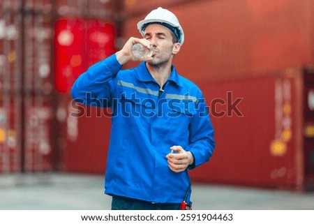 Logistics worker drinks water while taking a break at a shipping container yard. Emphasizing workplace hydration, occupational safety, and employee well-being in industrial environments.