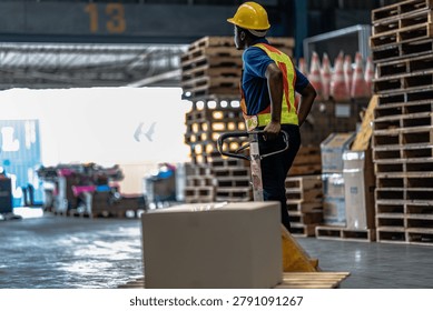 A logistics worker pulling a hand pallet jack loaded with a cardboard box towards a shipping dock container inside a commercial storage warehouse.