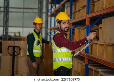 Logistics worker storing package boxes in a large distribution centre,Warehouse worker moving cardboard boxes while working with a colleague in a warehouse,.