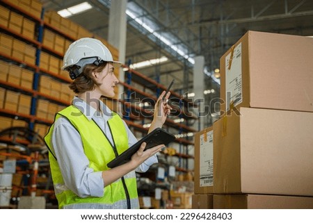 Logistics worker storing package boxes in a large distribution centre,Warehouse worker moving cardboard boxes while working with a colleague in a warehouse,.