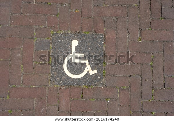 Logos for disabled on parking. handicap parking\
place sign on brick\
stones