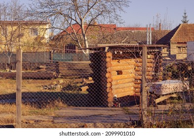 Logs, Boards In The Backyard. The Area Is Fenced With A Mesh Fence. Autumn Time. Daytime. Selective Focus. No People.