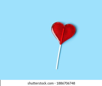 Lollipop heart on blue background. Sweet red heart shape candy on stick. symbol of love. Valentine's day, 14 february concept. romantic sweet gift