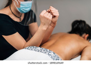 Lomilomi Practitioner Wearing A Protective Mask, Giving Back Massage With An Elbow At A Wellness Center