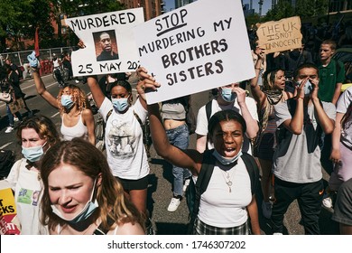 LONDON - 31ST MAY 2020: Black Lives Matters protesters in London holding signs and marching outside American Embassy wearing masks during lockdown coronavirus pandemic keeping 2 meters social distance
