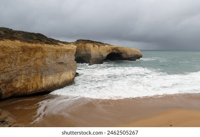 London Arch rock formation with ocean waves, sandy beach and cloudy sky on the Great Ocean Road in Victoria, Australia - Powered by Shutterstock