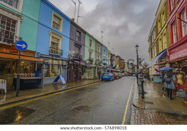 LONDON CITY - FEBRUARY, 2017: Corner shop\
and beautiful brightly coloured houses in the famous Notting Hill\
against a cloudy sky. London, United\
Kindom.