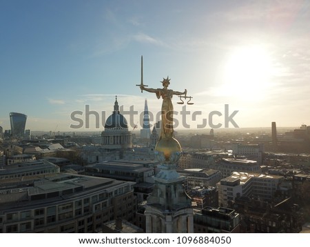 London city landscape drone view with golden lady justice statue in front of glaring sunshine