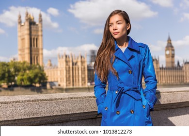 London city lifestyle Asian businesswoman Europe autumn travel in blue trench coat. Multiracial model in fashion fall outerwear at Westminster and Big Ben, famous european urban destination.
