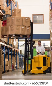 london, england, 02/02/2017 A man in an industrial warehouse lifting heavy product cardboard boxes off a shelf, with a small industrial forklift style device. - Shutterstock ID 666033934