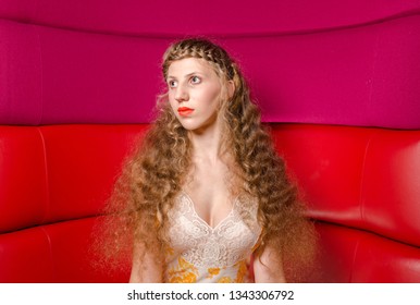 London, England, 05/0/2017 A Glamorous Woman With Platted Hair Braids And Platted Fringe Posing And Modelling For The Camera In A Pink And Red Leather Booth Background. Modelling Hair Styles.