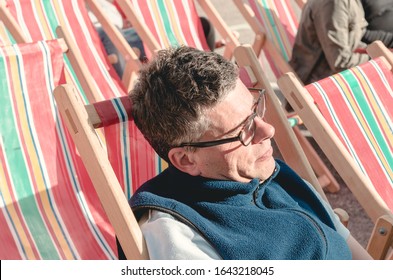 London, England, 05/05/2017, A Stylish Retro Vintage Fashionable Man Sat Relaxing , On A Retro Seaside Deckchair. Classic British Seaside Deckchair. Best Dressed Award. 