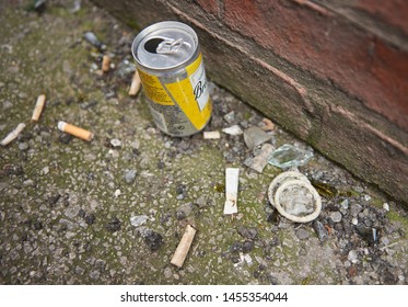 london, england, 05/05/2019 A dirty used latex rubber condom, surrounded by broken glass and cigarette butts, discarded in a dirty city alleyway. Safe sex prostitution sexual health. sexual disease 