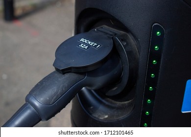 
London, England - ‎April 13 ‎2020: Close up of an electric vehicle recharging point in a residential road with an electric Taxi plugged in charging. 