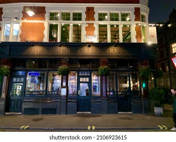 London, England - 21.12.2021. Fragment Of Facade Of “The Coach Makers Arms” Pub On Marylebone Lane. Dark Black Exterior With Stained Glass And Tables Outside. Night Time. Horizontal. Selective Focus