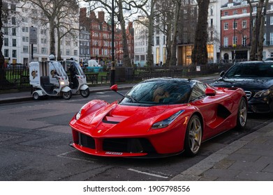 London, England - 24 December 2020: A red Ferrari LaFerrari in front of a Bentley-, and a Ferrari-showroom near Berkeley square, in Mayfair.