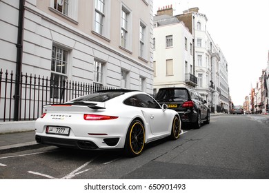 London, England - 24.05.2017: Porsche 911 Turbo S parked in Mayfair district in central London. This modern sport car is white coloured with golden yellow elements.