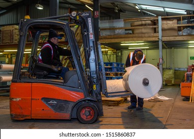 London, England, 28/01/2019 Colour Image Of A Forklift Lifting Wooden Pallet Onto A Rotating Industrial Lazy Susan For Wrapping A Stack Of Boxes Together In Plastic Wrap. Keeping Product Safe 